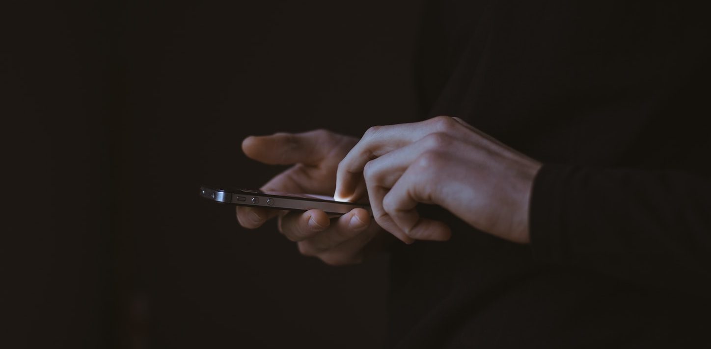 silhouette photo of person holding smartphone